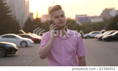 Handsome businessman talking mobile phone walking in the Street at Sunset. Handsome businessman talking mobile phone walking in the Street at Sunset. 61366952