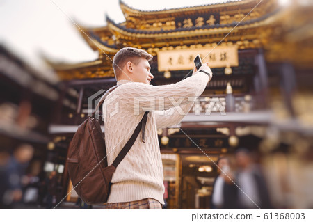 male tourist taking photos of a pagoda at Yuyuan market in Shanghai 61368003