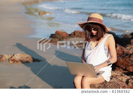 beautiful and cute businesswoman using laptop computer with sun glasses and hat on the beach during holiday vacation beautiful and cute businesswoman using laptop computer with sun glasses and hat on the beach during holiday vacation 61368382