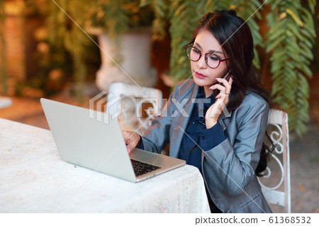 smart businesswoman with glasses working on laptop computer and cell phone smart businesswoman with glasses working on laptop computer and cell phone 61368532
