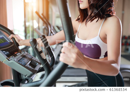 young healthy and sporty woman using exercise machine in gym young healthy and sporty woman using exercise machine in gym 61368534