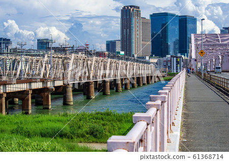 A view of the railway bridge and Umeda building over the Yodogawa river seen from Juso Ohashi, Yodogawa-ku, Osaka 61368714