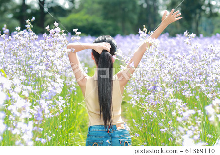 back view portrait of beautiful woman having a happy time and enjoying among flower 61369110