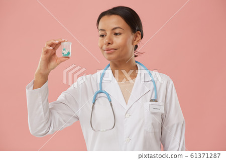 Female Doctor Holding Pills on Pink 61371287