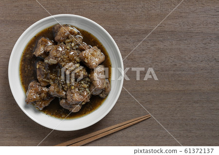 top view of stir fried pork rib with black pepper sauce in a ceramic dish on wooden table.  61372137