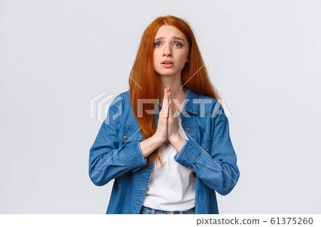 Waist-up portrait redhead uneasy and hopeful young girl begging for forgiveness, holding hands together in pray gesture, asking favour, supplicating, pleading and looking camera Waist-up portrait redhead uneasy and hopeful young girl begging for forgiveness, holding hands together in pray gesture, asking favour, supplicating, pleading and looking camera 61375260