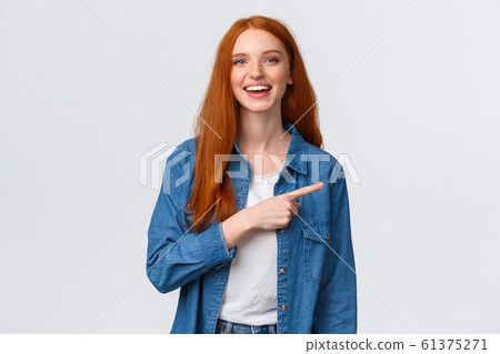 Carefree, friendly and happy outgoing redhead woman in denim shirt, pointing finger right and laughing at camera with beaming smile, standing white background, having discussion, communicate team Carefree, friendly and happy outgoing redhead woman in denim shirt, pointing finger right and laughing at camera with beaming smile, standing white background, having discussion, communicate team 61375271