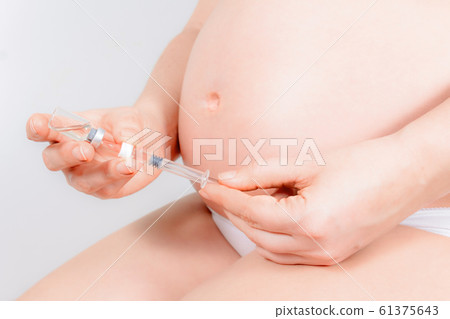 Unrecognizable pregnant woman is ready for injection. 61375643