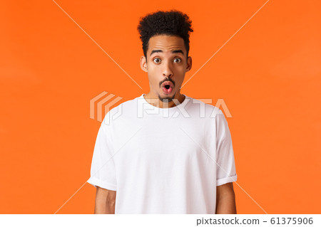 Surprises, amazement concept. Astonished and impressed handsome young college student, african-american guy, folding lips staring amazed, gasping wondered say wow, standing orange background 61375906