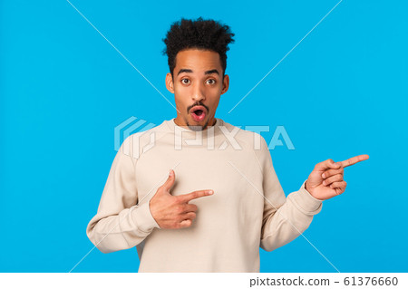 Questioned and impressed attractive african-american young male model with moustache, afro haircut, curious about event nearby, pointing fingers right, open mouth gasping amused, look wondered Questioned and impressed attractive african-american young male model with moustache, afro haircut, curious about event nearby, pointing fingers right, open mouth gasping amused, look wondered 61376660