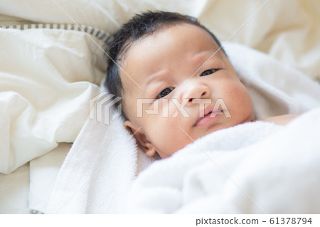 Funny infant baby boy lying on bed after wake up Funny infant baby boy lying on bed after wake up 61378794