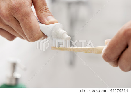 man using a bamboo toothbrush in the bathroom 61379214