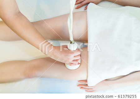 Body massage with cavitation. Young girl on massage table anti cellulite massage Body massage with cavitation. Young girl on massage table anti cellulite massage 61379255