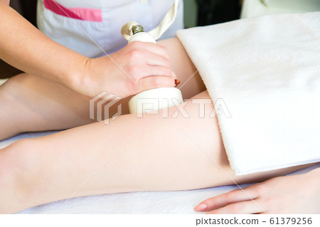 Body massage with cavitation. Young girl on massage table anti cellulite massage Body massage with cavitation. Young girl on massage table anti cellulite massage 61379256