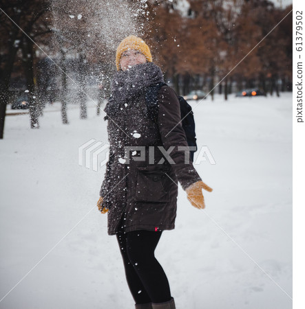 Happy young european woman in a yellow knitted hat and mittens with a backpack, laughs under the 61379502