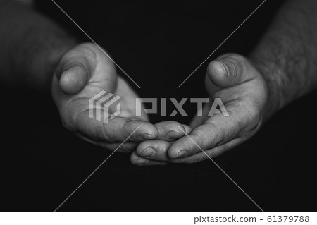 Low key, close up of hands of a faithful mature man praying, hands folded, interlaced fingers in Low key, close up of hands of a faithful mature man praying, hands folded, interlaced fingers in 61379788