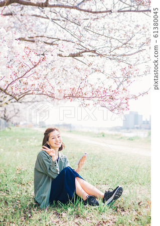 Woman listening to music under the cherry tree Woman listening to music under the cherry tree 61380045