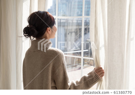 Woman opening curtain 61380770
