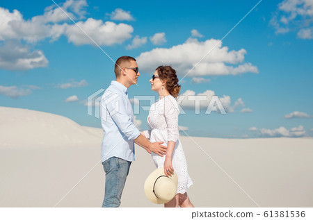 Young couple enjoying the sunset in the dunes. Romantic traveler walks in the desert. Adventure travel lifestyle concept Young couple enjoying the sunset in the dunes. Romantic traveler walks in the desert. Adventure travel lifestyle concept 61381536