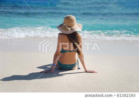 Silhouette of young woman on beach with hat Silhouette of young woman on beach with hat 61382165