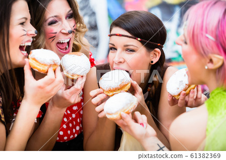 Girls at German Fasching Carnival eating doughnut-like traditional pastry 61382369