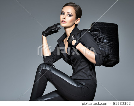 Beautiful woman in black holds fashion handbag Beautiful woman in black holds fashion handbag 61383392