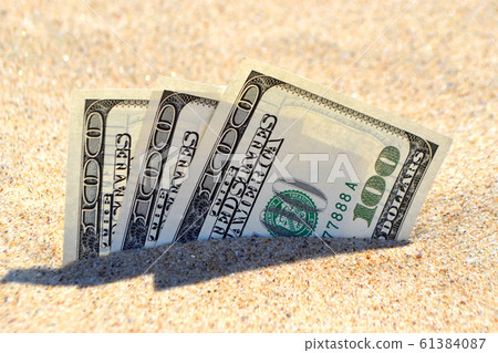 Money dolars half covered with sand lie on beach close-up. Money dolars half covered with sand lie on beach close-up. 61384087