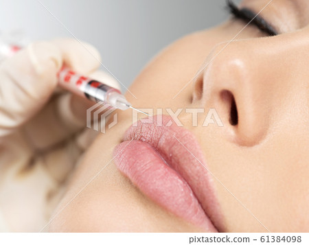 young woman gets botox injection in her lips young woman gets botox injection in her lips 61384098