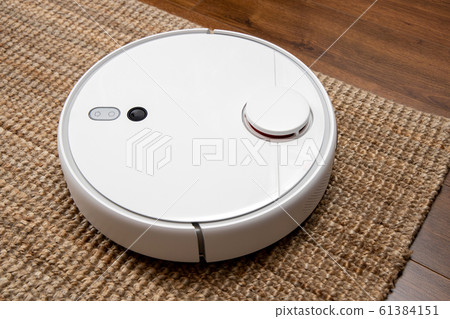 Robotic vacuum cleaner cleans the room from dust and debris, technological progress. Robotic vacuum cleaner cleans the room from dust and debris, technological progress. 61384151
