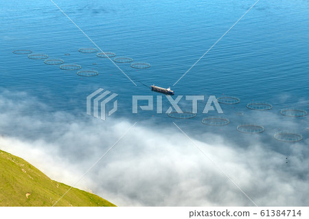 Fish farm with ship on foggy fjords of Funningur Fish farm with ship on foggy fjords of Funningur 61384714