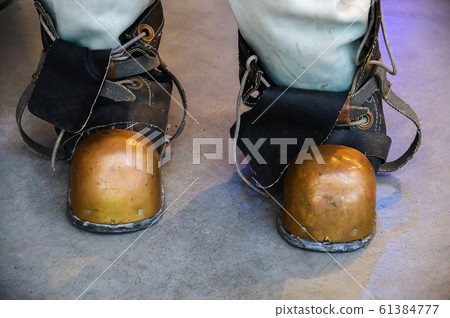 Close-up shoes of an old vintage three-bolt deep-sea diving suit. Suit for deep sea diving of the last century. The history of the study of the underwater world Close-up shoes of an old vintage three-bolt deep-sea diving suit. Suit for deep sea diving of the last century. The history of the study of the underwater world 61384777