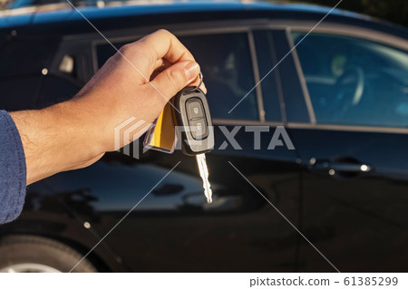 Close-up of man's hand holding keys to new car Close-up of man's hand holding keys to new car 61385299