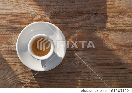 Cup of hot fresh coffee on wooden table on sunny day Cup of hot fresh coffee on wooden table on sunny day 61385300