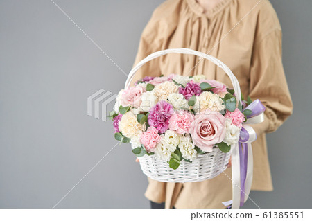 Flowers delivery. Flower arrangement in Wicker basket. Beautiful bouquet of mixed flowers in woman hand. Floral shop concept . Handsome fresh bouquet. 61385551