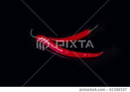 Two red chilli peppers on black background. Two red chilli peppers on black background. 61386587