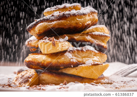 Pancakes with chocolate and banana and powdered sugar falling on top 61386837