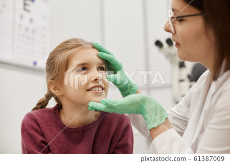 Female Ophthalmologist Examining Smiling Little Girl 61387009