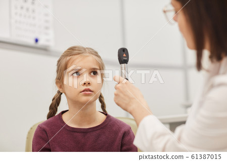 Female Ophthalmologist Examining Little Girl in Clinic 61387015