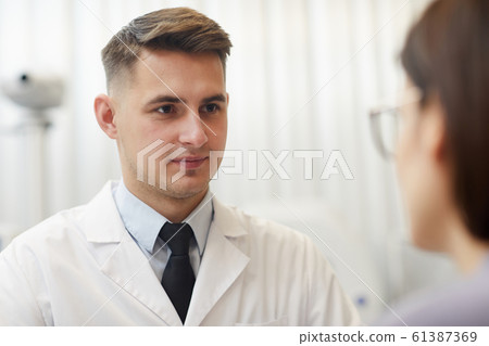 Handsome Doctor Listening to Female Patient 61387369