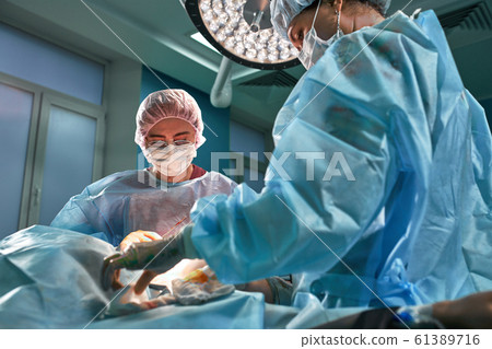 Group of surgeons in operating theater. Medical team performing surgery in operation room. 61389716