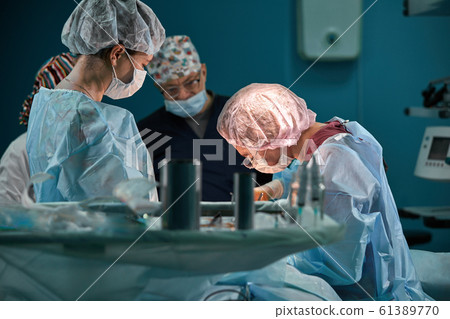 Group of surgeons in operating theater. Medical team performing surgery in operation room. Group of surgeons in operating theater. Medical team performing surgery in operation room. 61389770