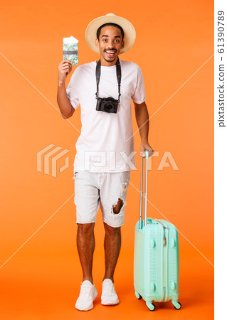 Full-length vertical shot african american happy boyfriend bought two tickets holidays luxury resort, holding luggage ready travel, standing airport terminal with passport, orange background Full-length vertical shot african american happy boyfriend bought two tickets holidays luxury resort, holding luggage ready travel, standing airport terminal with passport, orange background 61390789