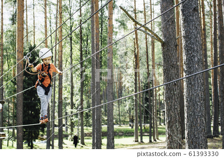 Little boy climbing rope trail. 61393330