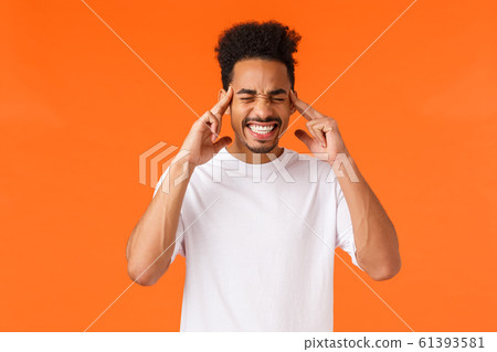 Distressed and tensed african-american male in white t-shirt, clench teeth, close eyes and touch temples, feeling migraine or headache, trying calm down and think straight, orange background Distressed and tensed african-american male in white t-shirt, clench teeth, close eyes and touch temples, feeling migraine or headache, trying calm down and think straight, orange background 61393581