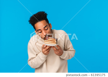 Tastes so good. Delighted and pleased african-american bearded guy likes sweets, attend friends birthday party, biting piece cake like taste, enjoy good food, standing blue background happy Tastes so good. Delighted and pleased african-american bearded guy likes sweets, attend friends birthday party, biting piece cake like taste, enjoy good food, standing blue background happy 61395175