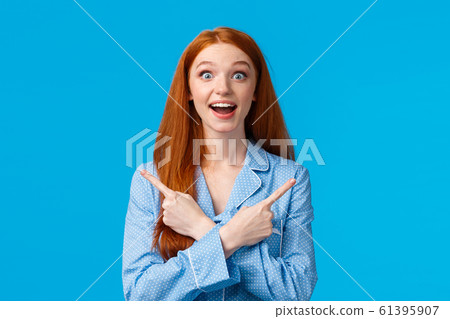 Surprised and amused beautiful redhead teenage girl, female college student playing with roommates in nightwear, pointing left and right, sideways with crossed hands amazed, see lots choices Surprised and amused beautiful redhead teenage girl, female college student playing with roommates in nightwear, pointing left and right, sideways with crossed hands amazed, see lots choices 61395907