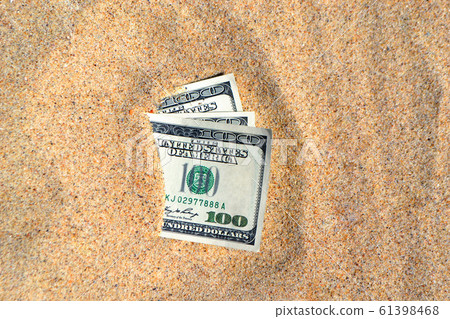 Money dolars half covered with sand lie on beach close-up Money dolars half covered with sand lie on beach close-up 61398468
