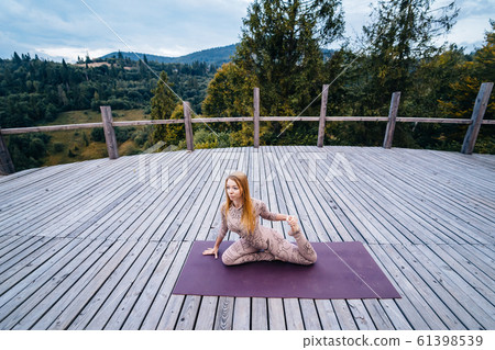 A woman practices yoga at the morning in a terrace on a fresh air. A woman practices yoga at the morning in a terrace on a fresh air. 61398539
