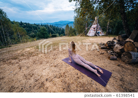 A woman practices yoga at the morning in a park on a fresh air. 61398541