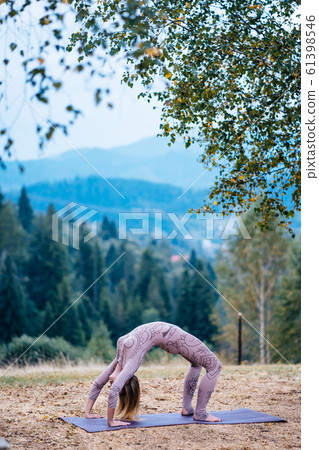 A woman practices yoga at the morning in a park on a fresh air. 61398546